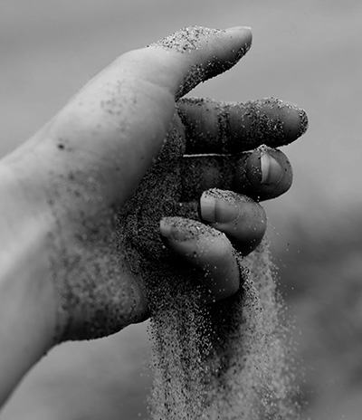 Sand der løber igennem fingrene på en hånd